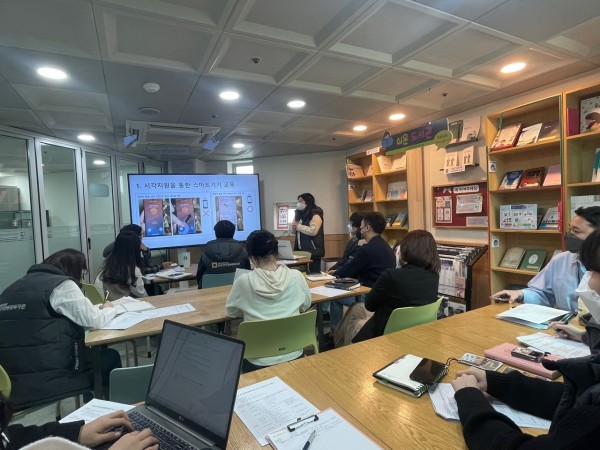 지역사회조직화팀에서 스마트폰 활용방법에 대한 교육을 진행했다고 설명하는 모습