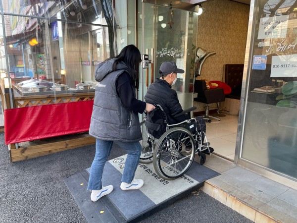 경사로를 이용하여 수동휠체어를 이동하는 모습