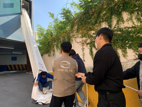 3층 구조대를 지지할 수 있게 지지대를 잡고있는 직원들과 대피하고 있는이용자