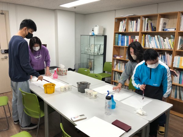 선생님이 도화지를 잡아주시고 그 위에 그림을 그릴 예정인 모습.