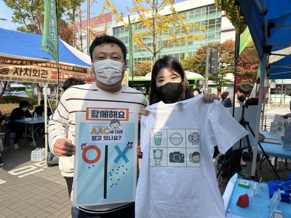 AAC 티셔츠와 스티커판을 들고 함께 사진 찍은 주민과 사회복지사