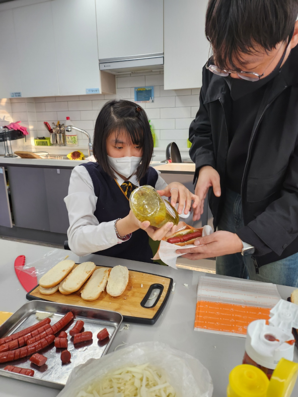 수제 핫도그에 소스를 뿌리는 모습