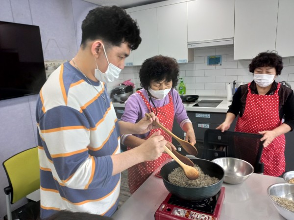 강사님의 도움을 받아 가스버너 위에 올려진 웍으로 멸치를 볶는 사진