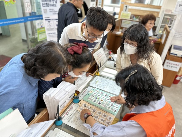 독산1동주민센터에 있는 의사소통 도움 그림글자판을 살펴보는 AAC모니터링단원과 밀알복지관 참여자들