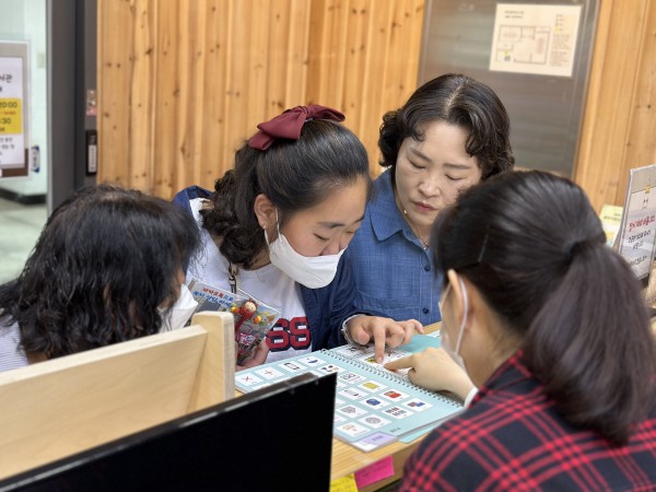 그림글자판으로 보고 싶은 책 위치를 손가락으로 짚어 도서관 사서님과 대화하는 모습