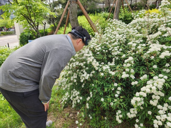 산책을 하다가 꽃냄새를 맡는 이용자