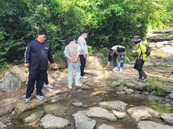 시흥계곡 계곡으로 내려가 계곡에 서식하는 새우와 도룡뇽 알을 구경하고 있는 이룸 아카데미 이용자 단체 사진