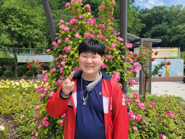 빨간 장미꽃 앞에서 활짝 웃고 있는 이용자