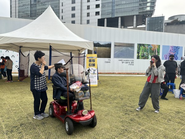 체험존에서 휠체어 탄 참가자 사진 찍어주는 모습