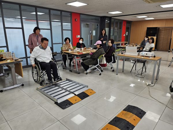 휠체어로 경사로 오르기 체험하는 모습