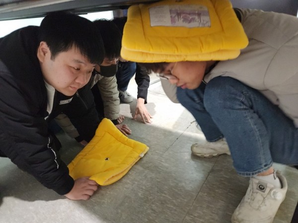 실내에서 지진이 발생하여 책상아래로 몸을 숨긴 훈련생들