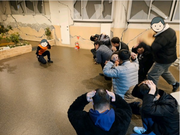 손으로 머리를 감싸고 앉아 실외 지진을 대처하는 훈련생들