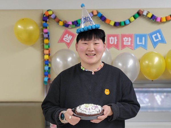 직접 만든 생일 케이크를 들고 환하게 웃는 이용자