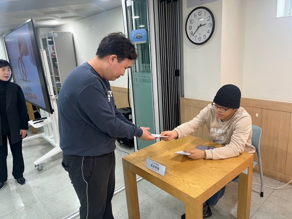 투표 실습을 위해 투표용지를 받고 있는 이용인분의 모습