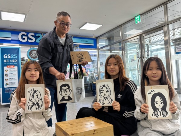 다함께 모여 완성된 캐리커쳐그림을 들은 모습