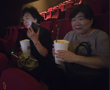 영화관에 입장해서 자리에 앉아서 참여자들이 이야기하는 모습