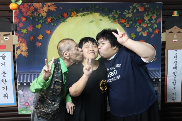 포토존에서 볼뽀뽀하며 사진찍는 이용인 가족