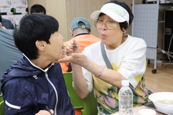 이용인에게 식사를 먹여주는 보호자