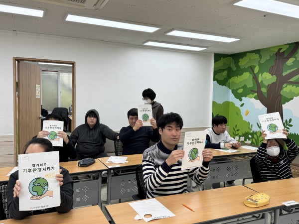 모두 완성된 책자를 들고 웃는 하누리주간보소센터 이용인의 모습