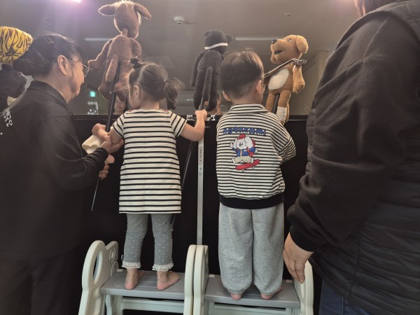 아이들이 발판을 딛고 올라가 인형극을 하는 모습
