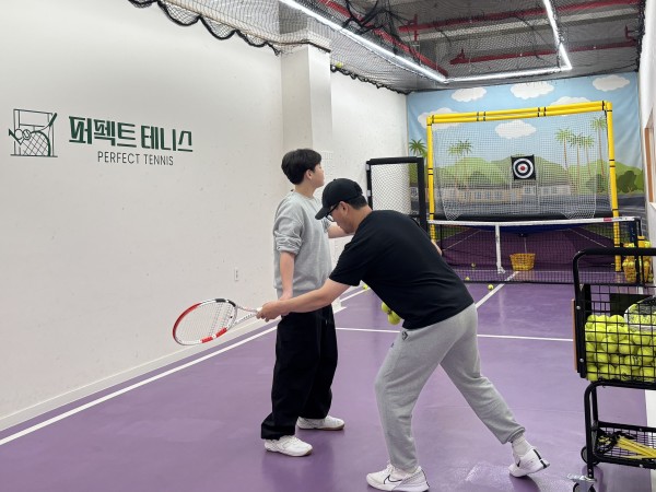 코치가 동생에게 테니스 포즈 피드백을 주고 있는 모습