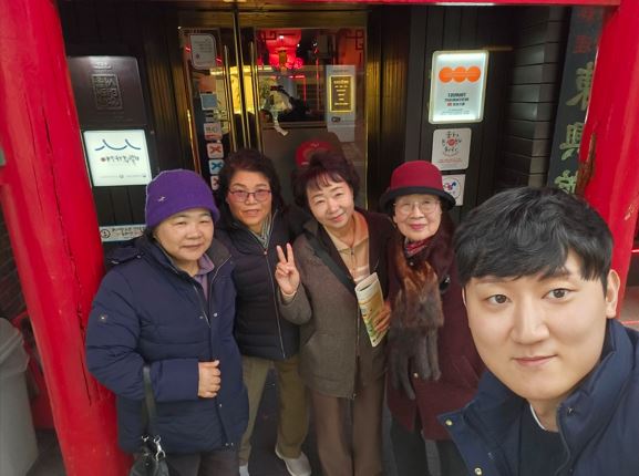 송년회를 하기 전 식당앞에서 보호자,담당자가 함께 단체사진을 찍는 모습