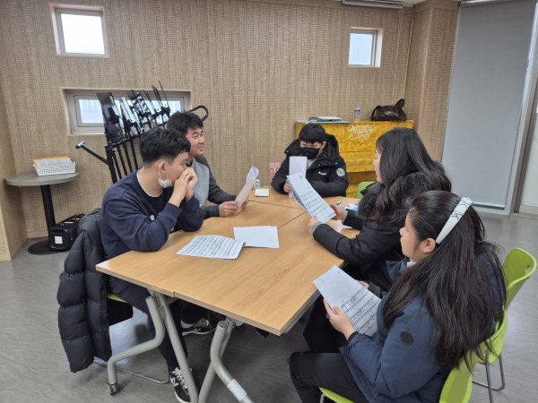 책상에 둘러앉아 함께 악보를 보노래 부르는 사진