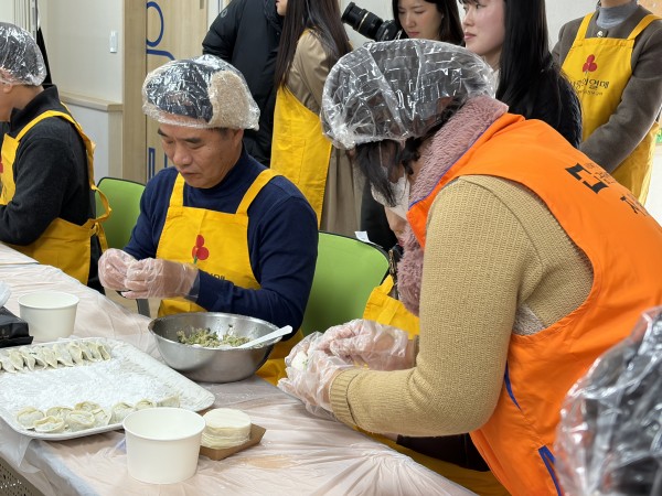 만두 모양을 예쁘게 만들수 있도록 알려주고 있는 봉사자 모습