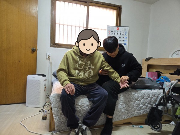 치료사가 이용인의 마비측 팔을 마사지 하고 있다