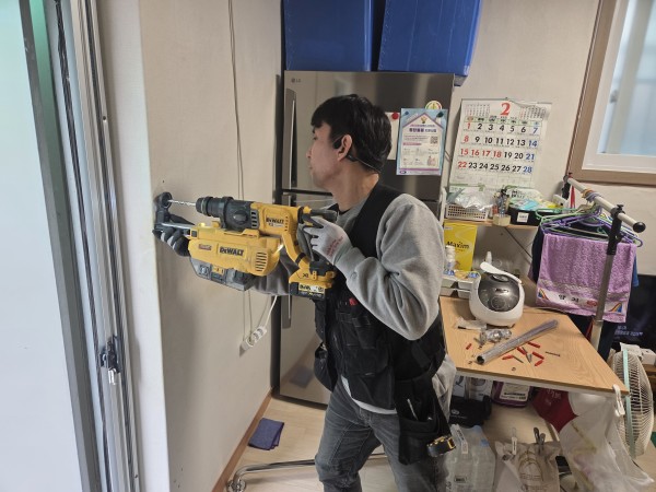 핸드레일 설치를 위해 벽에 구멍을 뚫고 있다