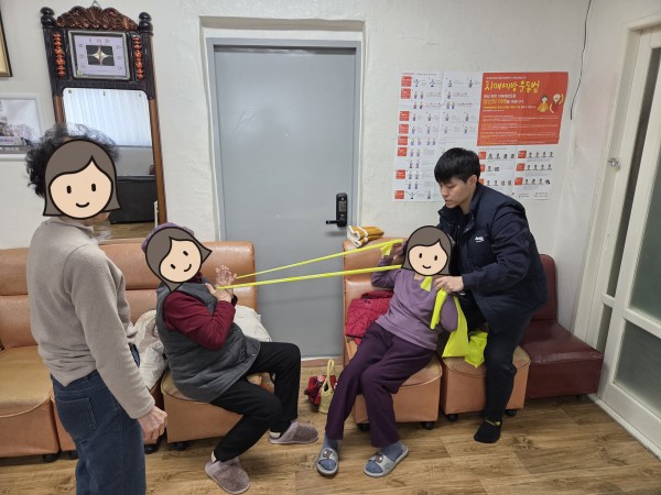 이용인 둘이 짝을 지어 탄력밴드를 당기는 운동을 하고 있다