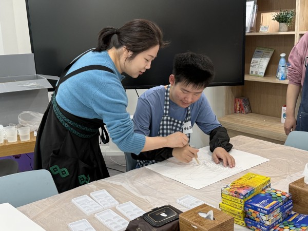 강사와 함께 손을 잡고 그림을 그리는 신규 참여자