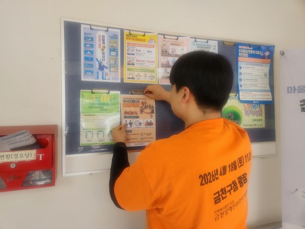 아파트 내 게시판에 홍보 포스터를 게시하고 있다