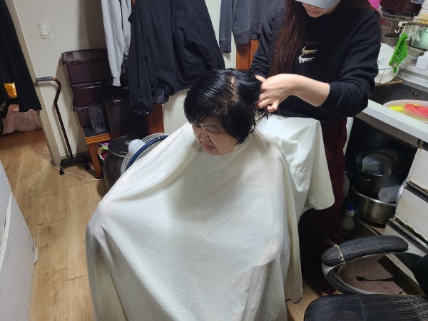 거실에서 머리를 자르는 이용인의 모습