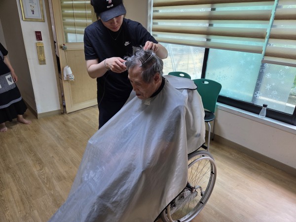 휠체어 위에서 이발하는 이용인의 모습