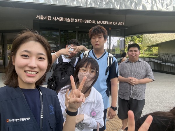 미술관 앞에서 환하게 웃고 있는 이용자들